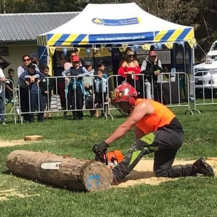 Arborist cross-cutting a log with a chainsaw outdoors
